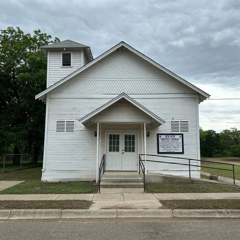 The white clapboard New Hope Baptist Church with a bell tower and church sign on College Street in Lampasas